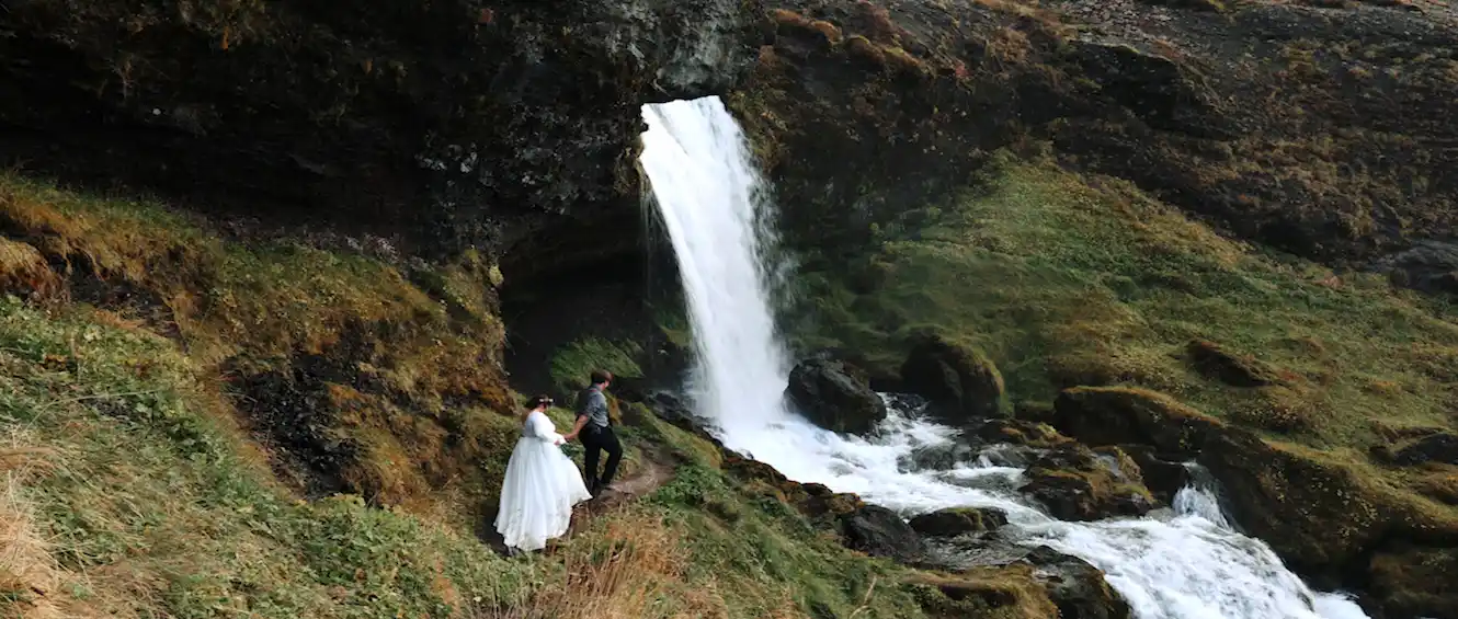 Couple embrace at an Iceland waterfall during their elopement ceremony