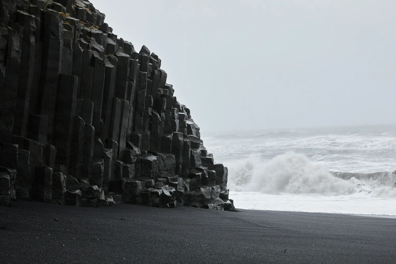 Waves crash against shore at Reynisfjara black sand beach Iceland