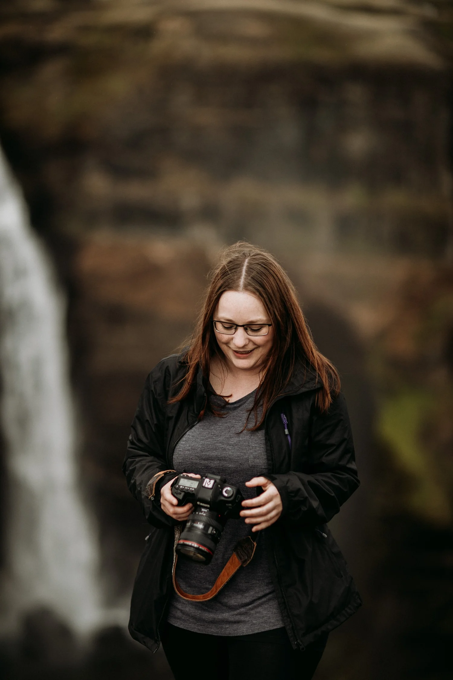 Iceland videographer holds camera with waterfall in background