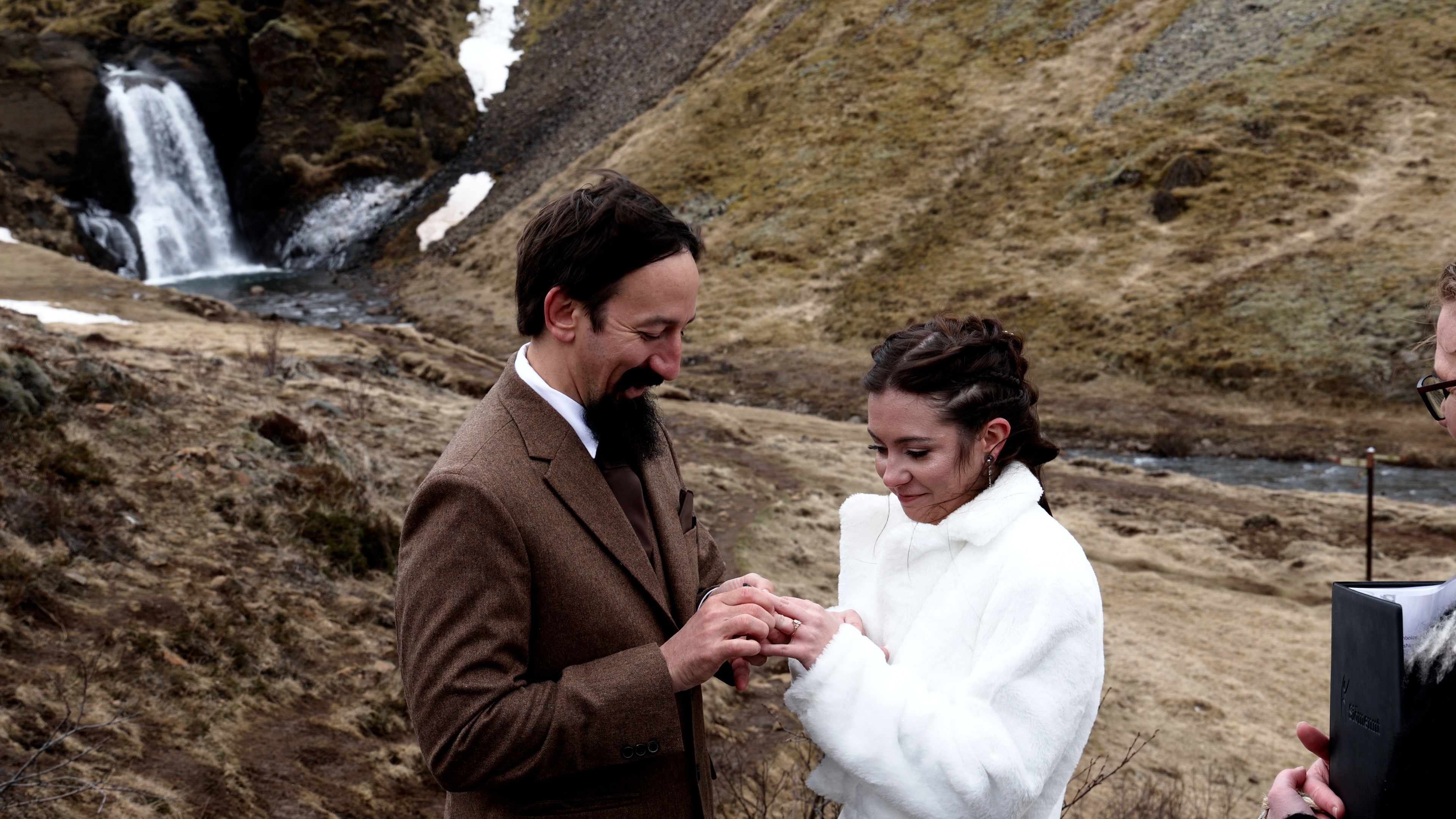 Couple exchanging rings at a waterfall during their Iceland elopement