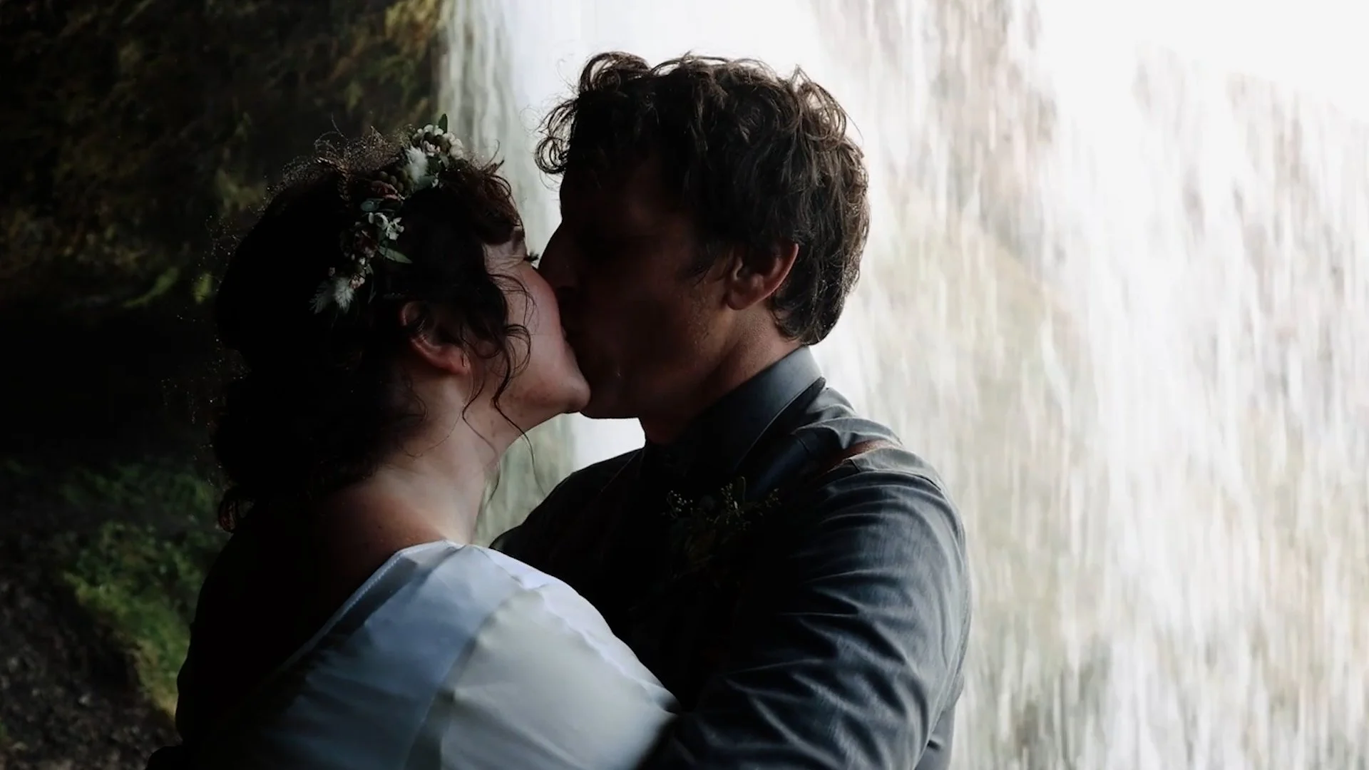 Couple kissing under a waterfall bride and groom at a waterfall during their Iceland elopement