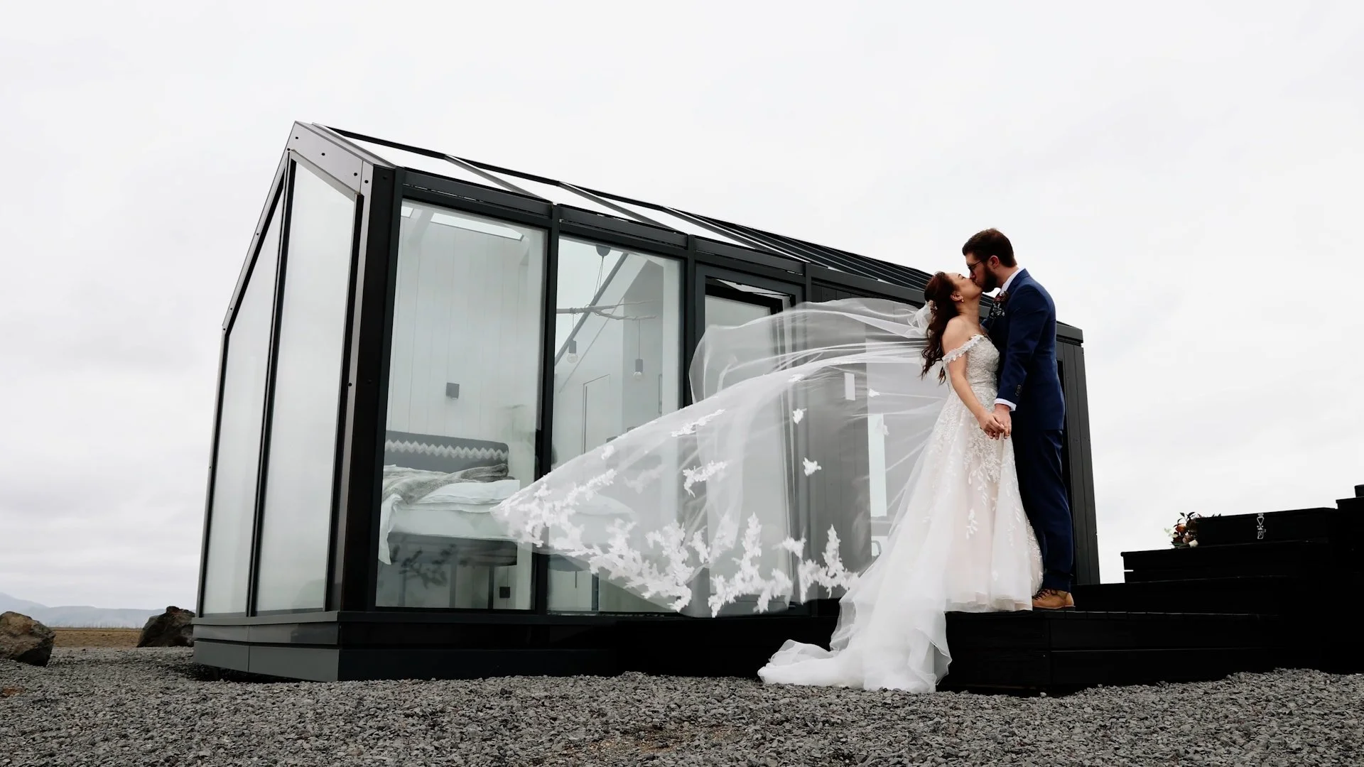 Bride and groom kissing at glass cottages veil in wind glass lodge accommodation during an Iceland elopement south coast